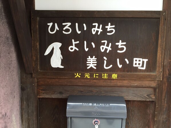 A wooden sign with Japanese characters and a white rabbit illustration, a metal mailbox, and a wooden door frame.