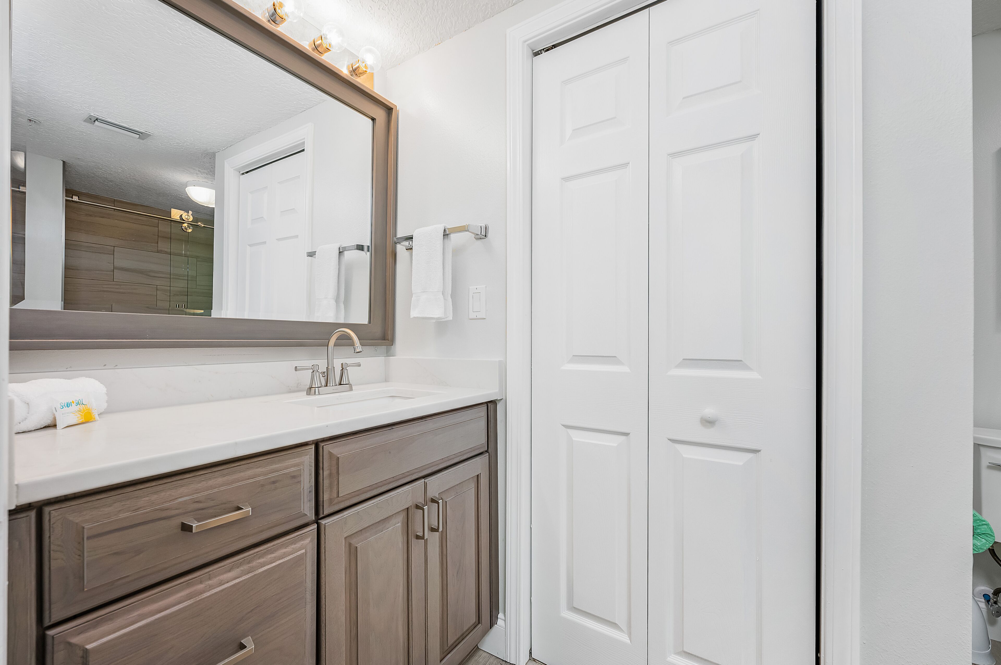 A bathroom with a white vanity, a large mirror, and a white door.
