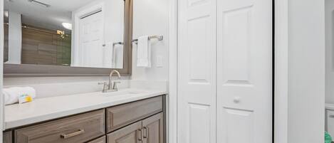 A bathroom with a white vanity, a large mirror, and a white door.