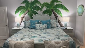 A bedroom with a bed, two nightstands, a door, and a wall with a decorative piece.
