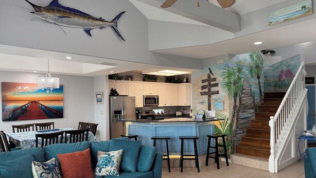 A spacious living area with a kitchen, a dining area, and a staircase leading to a second floor.