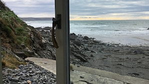 A coastal view with a rocky beach, a concrete path, and a metal door frame. - In an exceptional position right on the beach is this spacious and comfortable cottage - a perfect g (Truro)