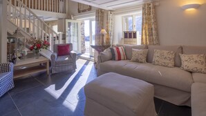 A spacious living area with a staircase, a sofa set, and a coffee table. - In an exceptional position right on the beach is this spacious and comfortable cottage - a perfect g (Truro)