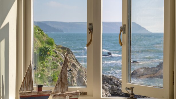 A window with two small sailboats and a view of the ocean. - In an exceptional position right on the beach is this spacious and comfortable cottage - a perfect g (Truro)