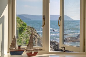A window with two small sailboats and a view of the ocean.