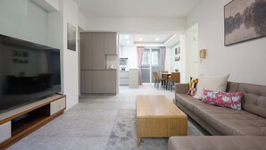 A modern living room with a flat-screen TV, a wooden coffee table, a beige sofa with patterned cushions, and a dining area in the background. - H&K 3/2 New Deco Taipei 101/WTC MRT 1 minute TICC (Taipei City)