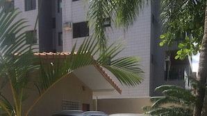 A parking area with two cars, a building with a tiled facade, and a palm tree. - BEAUTIFUL HOUSE WITH AN UNMISSABLE OUTDOOR AREA!!!! (Balneario Guarujá)