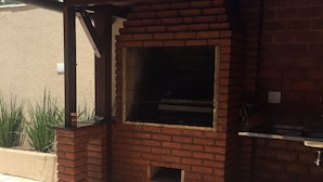 An outdoor brick fireplace with a chimney, surrounded by a patio area with chairs and a table. - BEAUTIFUL HOUSE WITH AN UNMISSABLE OUTDOOR AREA!!!! (Balneario Guarujá)