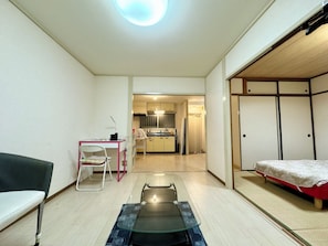Een ruimtelijk ingerichte leefruimte met een kitchenette, een bed, een eettafel en een stoel.