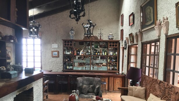 Eine gemütliche Bar mit Holzbalken, Barhocker und einer Sitzecke mit einer Couch und Sesseln.