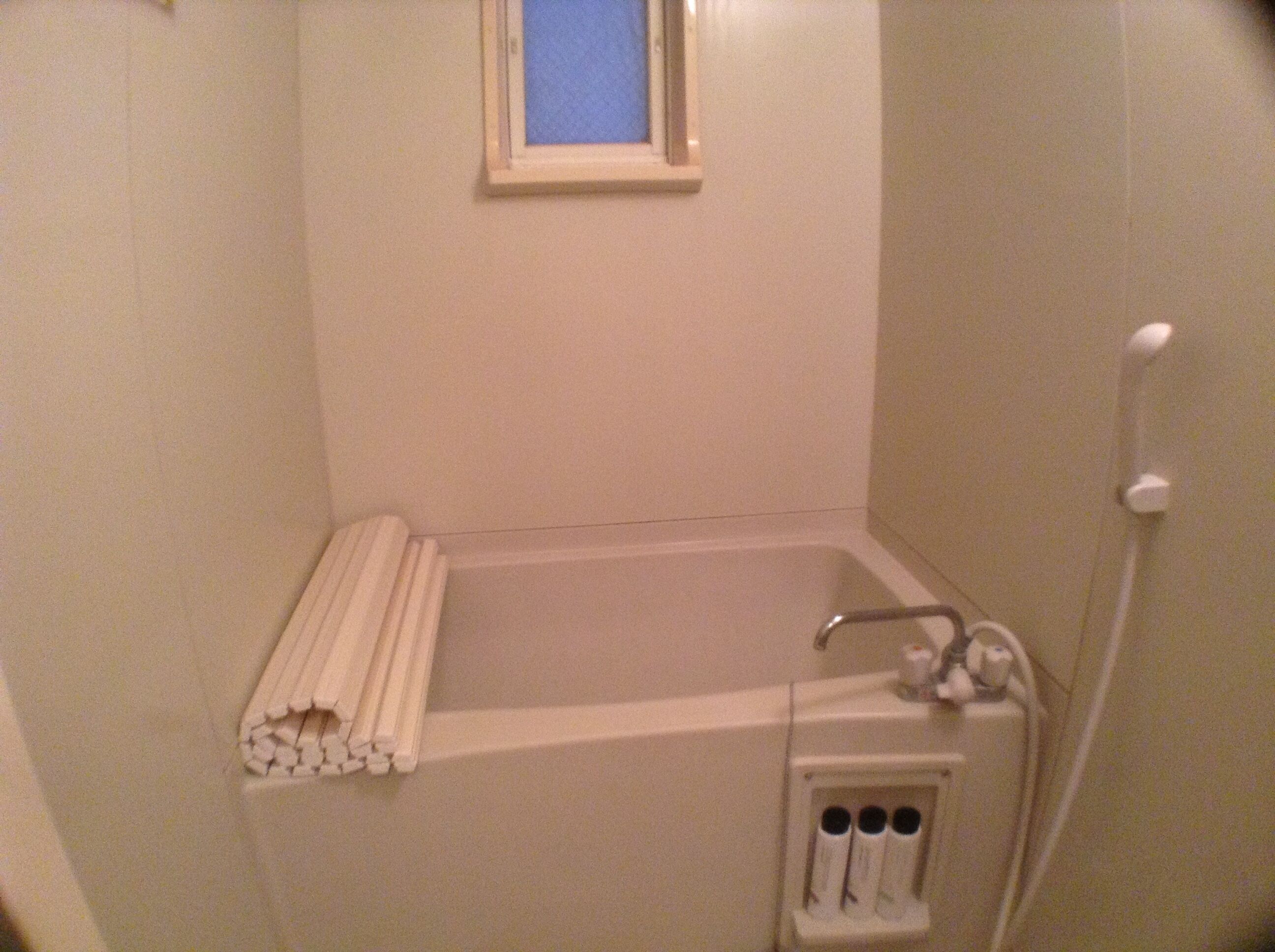 Ein kleines, abgeschlossenes Badezimmer mit Badewanne, Fenster und Handtuchhalter.