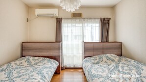 A room with two beds, a window with curtains, an air conditioning unit, and a ceiling light fixture. - Free Parking&Wifi/KIX&USJ 30min/max8ppl (Sakai-shi)