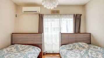Ein Zimmer mit zwei Betten, einem Vorhangfenster, einer Klimaanlage und einer Deckenleuchte.