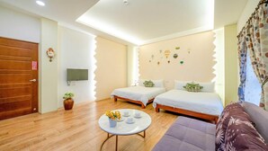 A cozy room with two beds, a sofa, a TV, and a small table with flowers. - Aurora Castle (Luodong)