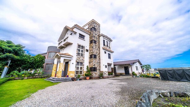 A large, multi-story house with a prominent stone tower, a well-maintained lawn, and a gravel driveway. - Aurora Castle (Luodong)