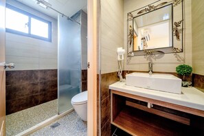 A modern bathroom with a glass shower enclosure, a white toilet, a vanity with a mirror, and a small plant on the counter. - Aurora Castle (Luodong)