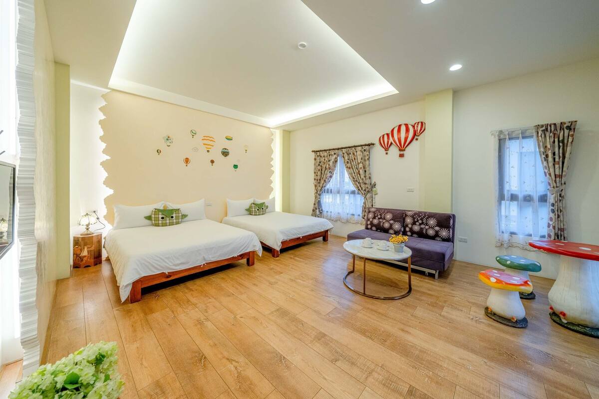 A cozy room with two beds, a sofa, a round table, and a unique mushroom-shaped table.