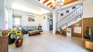 A spacious living area with a sofa, coffee table, and a large vase of sunflowers. A staircase with a decorative railing leads to an upper level. - Aurora Castle (Luodong)
