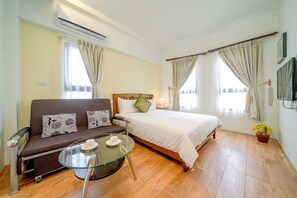 A room with a bed, a sofa, a glass table, and a TV. - Aurora Castle (Luodong)