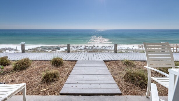 A wooden boardwalk leading to the beach with white chairs and a sign. - Crystal Sands #101B * Beach Chair Set Included * Salt Water Vacations (Destin)