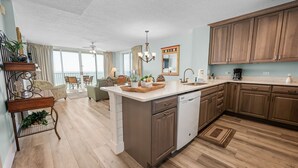 A spacious kitchen with wooden cabinets, a central island, and a dining area with a view. - Island Princess 416 * Gulf front~Beach Chair Set Included * Salt Water Vacations (Fort Walton Beach)