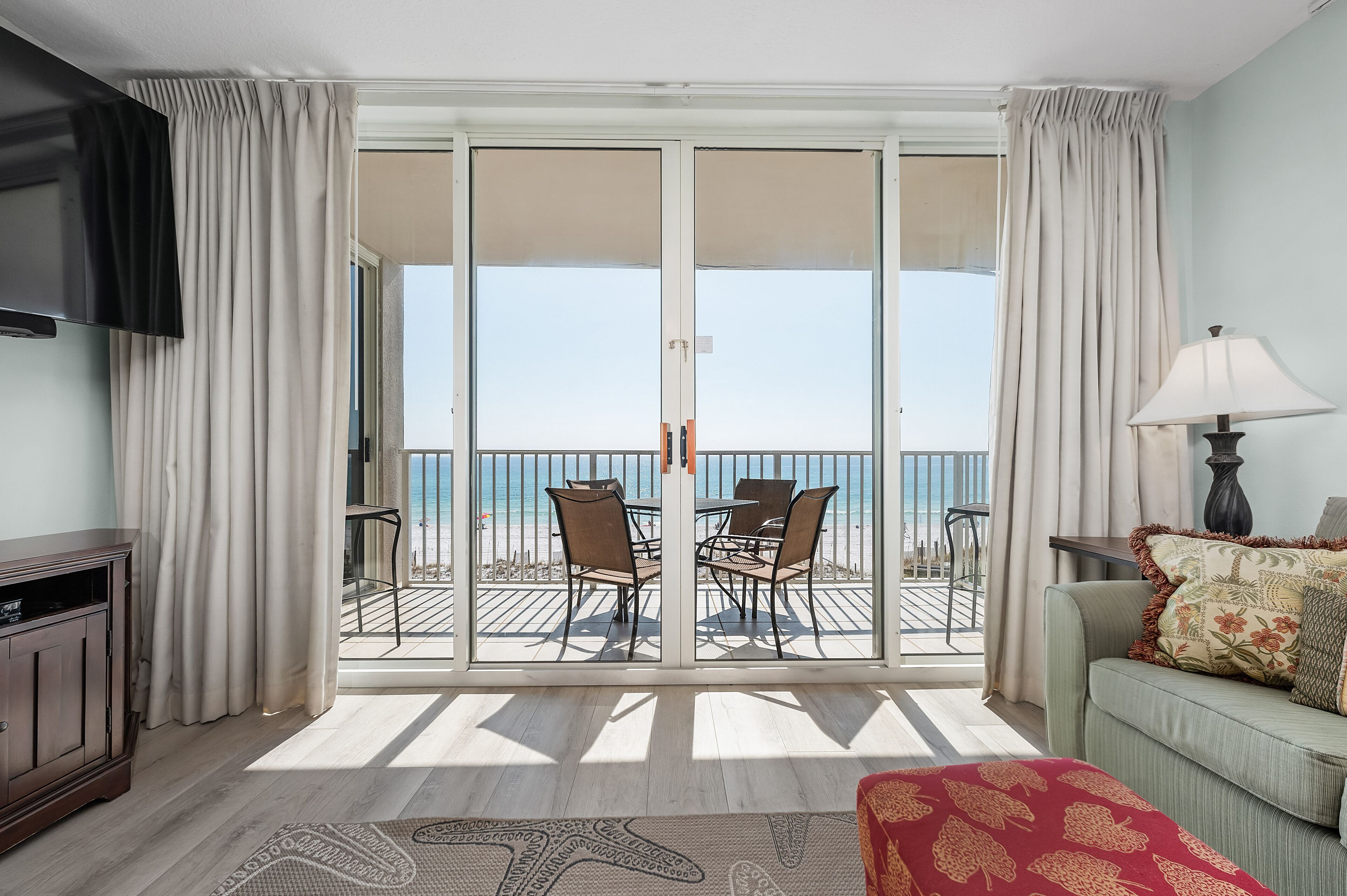 A room with a balcony, a sofa, a TV, and a lamp.
