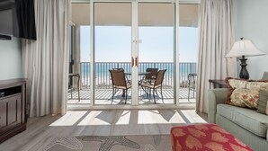 A room with a balcony, a sofa, a TV, and a lamp. - Island Princess 416 * Gulf front~Beach Chair Set Included * Salt Water Vacations (Fort Walton Beach)