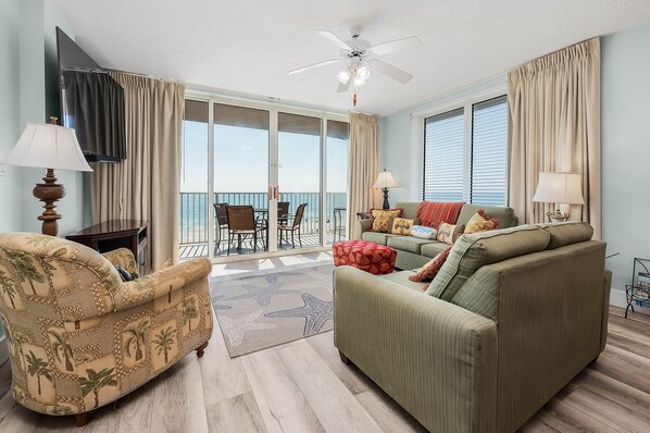 A spacious living room with a sofa, armchair, and a dining area with a table and chairs.