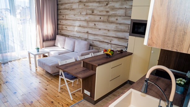 Une cuisine moderne avec des meubles en bois, un four encastré et un évier doté d’un robinet incurvé.
