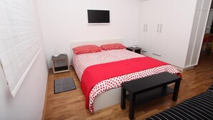 Ein Schlafzimmer mit Bett, Nachttisch, Kleiderschrank, einer Bank und einem kleinen Teppich.