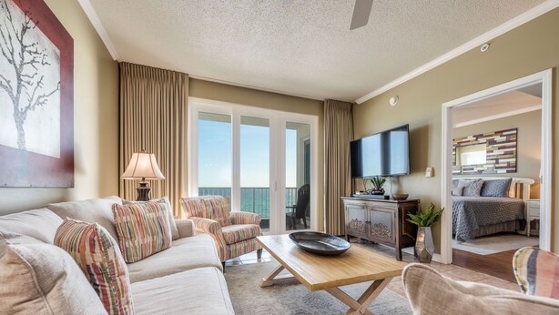 A spacious living room with a sofa, armchairs, a coffee table, and a television.