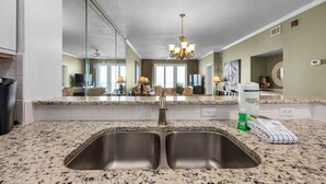 A kitchen with granite countertops, a double sink, and a chandelier.