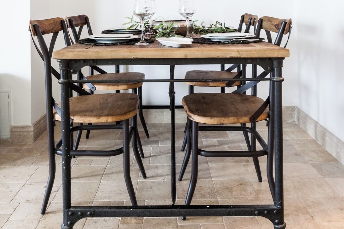 Una mesa de comedor con cuatro sillas, una obra de arte enmarcada de un flamenco y una copa de vino sobre la mesa.