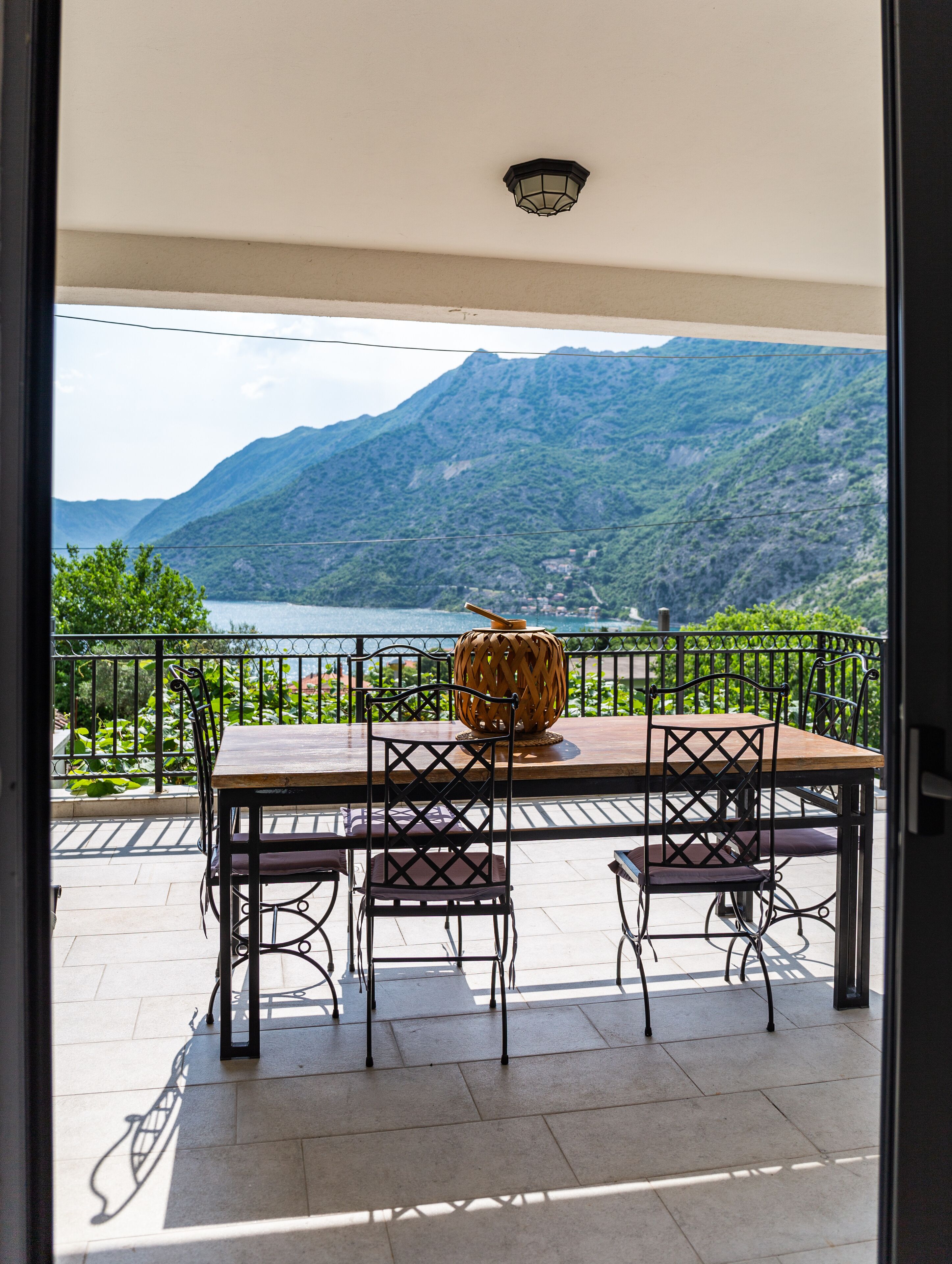 An outdoor dining area with a table and chairs, a decorative vase, and a view of a lake and mountains.