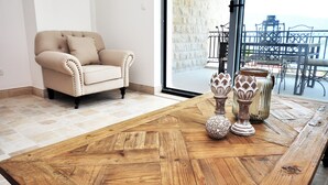 Ein Zimmer mit einem beigefarbenen Sessel, einem Holztisch mit Fischgrätmuster und dekorativen Vasen.