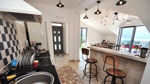 Eine moderne Küche mit einer großen Spüle, Barhocker und Blick auf den Balkon.