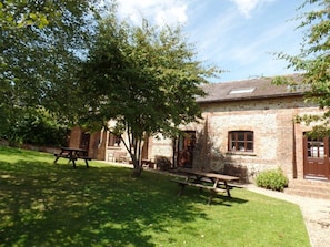 Situated in a serene natural setting, this charming building features a traditional design with a pitched roof and a cozy porch area.
