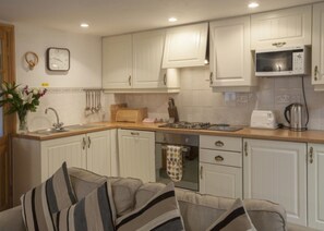 Compact kitchen with sink, toaster, kettle, and microwave, adjacent to a cozy seating area.