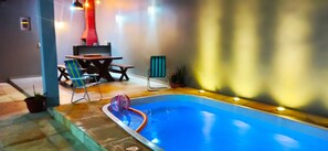 Ein Schwimmbecken mit Whirlpool, umgeben von Sitzgelegenheiten im Freien und einem Grillplatz.