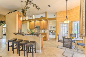Una cocina amplia con una isla central, taburetes de bar e iluminación colgante.