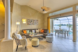 Amplia sala de estar con un sofá grande, sillones, una mesa de centro y un juego de comedor junto a un ventanal con vista a una piscina.