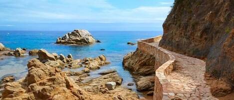A coastal pathway with rocky terrain and a clear view of the sea.
