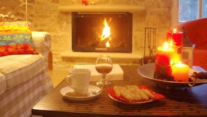 Una stanza accogliente con un camino, un tavolo con una candela, una tazza di caffè e un piattino di biscotti.