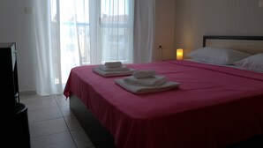 A hotel room with a bed, pillows, a bedside lamp, and a window with curtains.