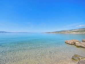 Una vista limpida di un mare calmo e di una costa rocciosa.