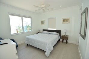 A bedroom with a bed, a desk, a ceiling fan, and two bedside tables. - High-end New Home - Large PRIVATE Pool, Snorkeling, Cliff Jumping, Kayaks & SUP (Eleuthera)