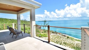 A balcony with a view of the ocean, a chair, and a railing. - High-end New Home - Large PRIVATE Pool, Snorkeling, Cliff Jumping, Kayaks & SUP (Eleuthera)