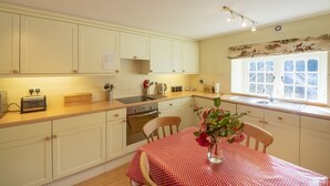 A kitchen with white cabinets, a wooden countertop, a red and white checkered tablecloth, and a vase with flowers. - Spacious, self contained flat within this Historic Castle of Caerhays, within walking distance of th (Saint Austell)