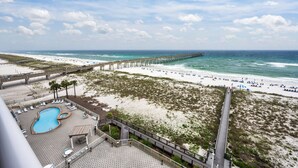 A beach view with a pier extending into the ocean, a swimming pool, and beach chairs. - Summerwind Resort 602 Center * Beach Chair Set Included * Salt Water Vacations (Navarre)