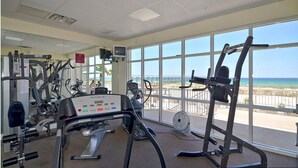 A gym with cardio machines, weight equipment, and a view of the beach. - Summerwind Resort 602 Center * Beach Chair Set Included * Salt Water Vacations (Navarre)
